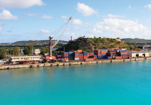 Cargo containers and a crane beside the water at a small port.