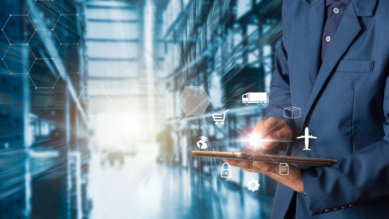 Person using a tablet in a warehouse with digital freight and logistics icons.